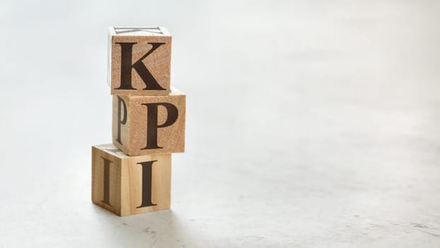 Pile with three wooden cubes - letters KPI meaning Key Performance Indicator on them, space for more text / images at right side.