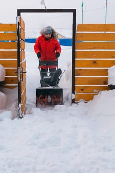 A man clear snow from backyard with snow blower. Winter season and snow blower equipment.