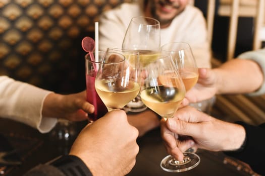 Clinking glasses with white wine and toasting at a restaurant