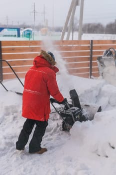 A man clear snow from backyard with snow blower. Winter season and snow blower equipment.