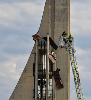 HUSTOPECE, CZECHIA - JULY 27, 2023: Firefighters at the church tower. Firefighter intervention at a high-rise building. Wind blew off the roof sheathing.