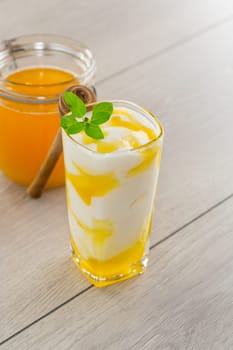 prepared homemade yogurt with natural honey in a glass on a light wooden table.