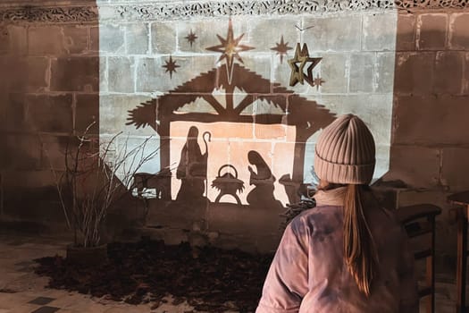 A child looks at christmas creche with Joseph Mary and small Jesus