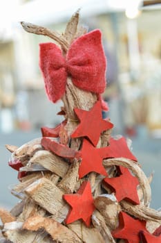 red bow and wooden stars on top of a wooden Christmas tree