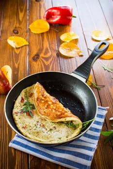 Fried omelets with various autumn vegetables in a frying pan on a wooden table. Autumn recipes.