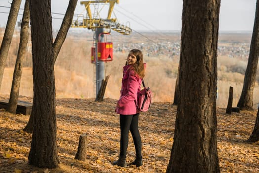 Back view of a girl walking on autumn park in fall season. Millennial generation and youth.