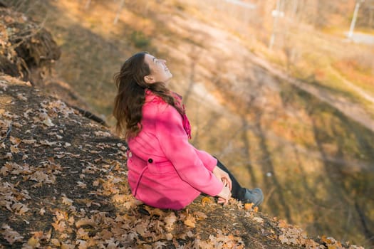 Beautiful happy smiling girl with long hair wearing black hat and pink jacket posing in autumn park. Outdoor portrait day light. Autumn mood concept. Copy empty space for text.