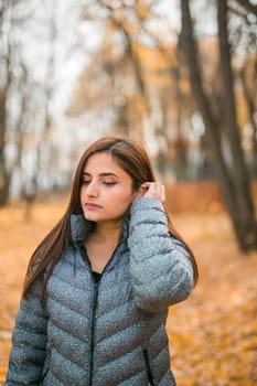 Beautiful indian woman generation z relaxing and feeling nature at autumn park in fall season. Diversity and gen z youth.