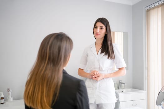 Female professional beauty doctor talking with young female. Beauty therapist talks to client about facials procedure. Dermatologist and patient in clinic