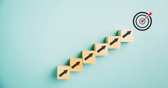 Target icon positioned on wooden blocks with upward arrows, depicting the progress. Blue background signifies business growth, while conveying concepts of profit, investment, and economic improvement.