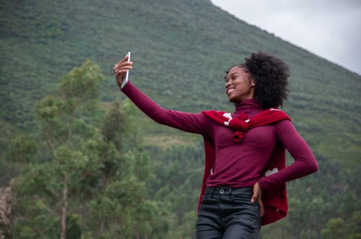 afro influencer girl streaming on a mountainside. High quality photo