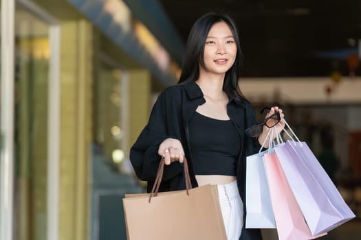 Young asian woman in shopping. Fashion woman in black with shopping bag walking around the city after shopping. Black friday.