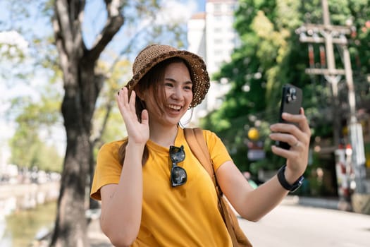 happy young Asian tourist taking picture with a smartphone while visiting a Chinese temple.