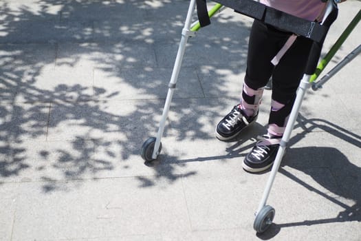 child with walking frame and knee orthosis outdoor .