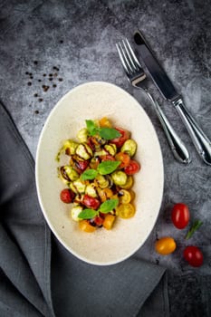 salad of yellow and red cherry tomatoes of different varieties with herbs