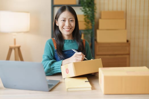 Starting small business entrepreneur of independent Asian female online seller packing products to send to customers and SME delivery concept.