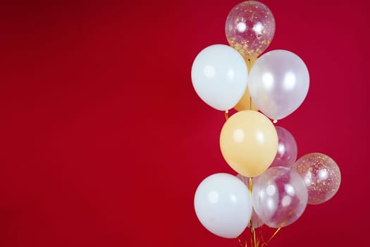 Light balloons - white, beige, transparent, pearl on a red background. Horizontal photo. Space for text. High quality photo