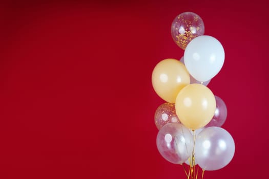 Light balloons - white, beige, transparent, pearl on a red background. Horizontal photo. Space for text. High quality photo