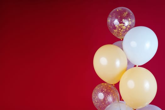 Light balloons - white, beige, transparent, pearl on a red background. Horizontal photo. Space for text. High quality photo