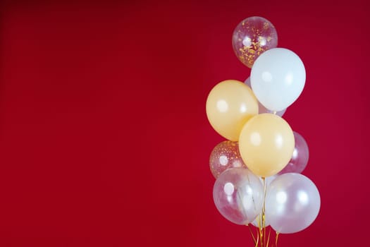 Light balloons - white, beige, transparent, pearl on a red background. Horizontal photo. Space for text. High quality photo