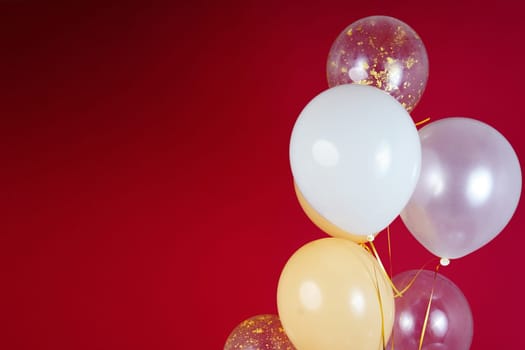 Light balloons - white, beige, transparent, pearl on a red background. Horizontal photo. Space for text. High quality photo