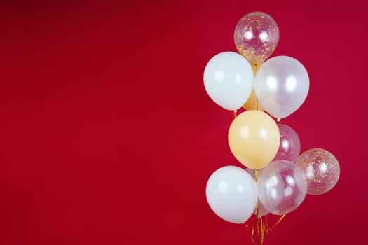 Light balloons - white, beige, transparent, pearl on a red background. Horizontal photo. Space for text. High quality photo