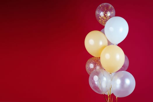 Light balloons - white, beige, transparent, pearl on a red background. Horizontal photo. Space for text. High quality photo