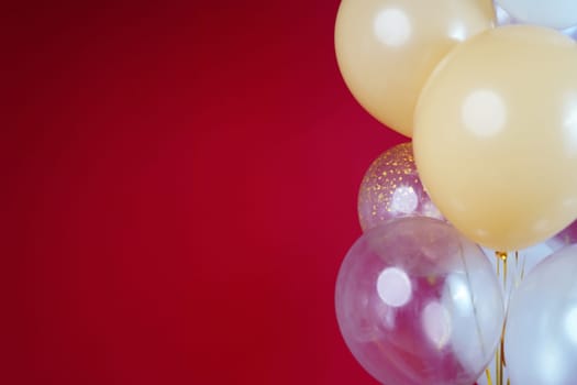 Light balloons - white, beige, transparent, pearl on a red background. Horizontal photo. Space for text. High quality photo