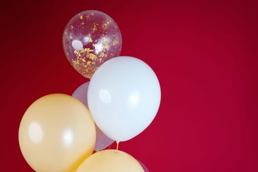 Light balloons - white, beige, transparent, pearl on a red background. Horizontal photo. Space for text. High quality photo