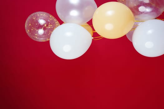 Vertical photo of white and transparent balloons on red burgundy background. Space for text. High quality photo