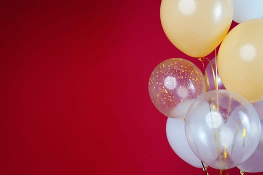 Light balloons - white, beige, transparent, pearl on a red background. Horizontal photo. Space for text. High quality photo