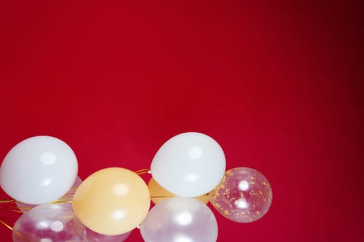 Vertical photo of white and transparent balloons on red burgundy background. Space for text. High quality photo