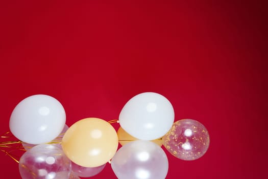 Vertical photo of white and transparent balloons on red burgundy background. Space for text. High quality photo