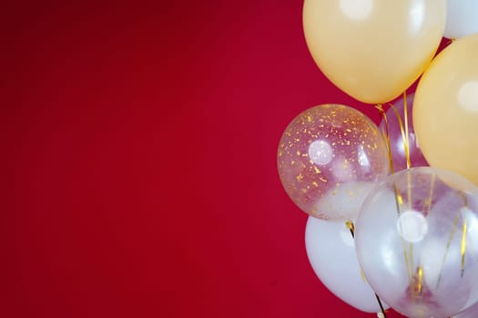 Light balloons - white, beige, transparent, pearl on a red background. Horizontal photo. Space for text. High quality photo