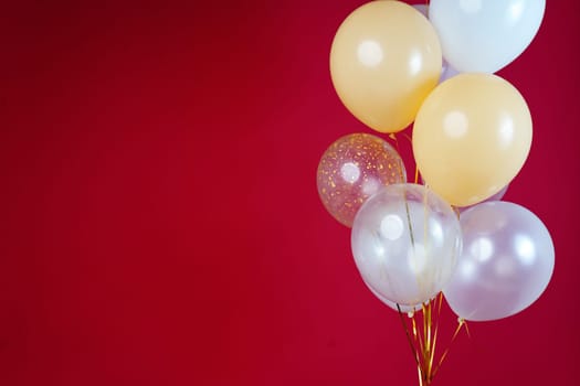 Light balloons - white, beige, transparent, pearl on a red background. Horizontal photo. Space for text. High quality photo