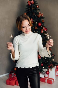 woman with sparklers at christmas tree new year