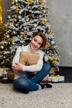 Woman opening gifts at christmas tree with gifts