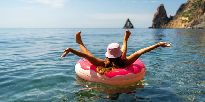 Summer vacation woman in hat floats on an inflatable donut mattress. Happy woman relaxing and enjoying family summer travel holidays travel on the sea