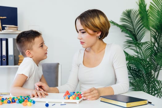 Teacher playing educational games with little boy at school