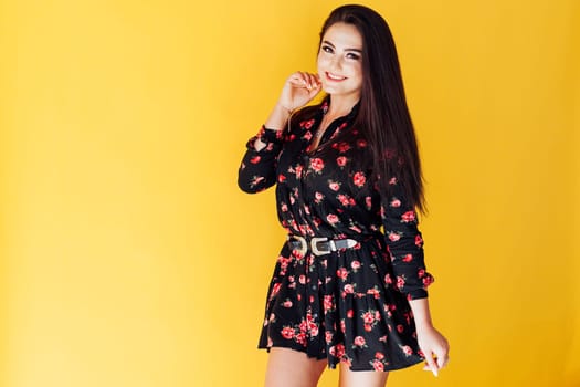 brunette woman in dress with flowers on yellow background