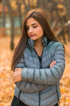 Beautiful indian woman generation z relaxing and feeling nature at autumn park in fall season. Diversity and gen z youth.