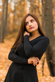 Close up portrait of pretty indian young woman enjoying warm autumn sunny day vacation outdoors. Generation z and gen z concept. Fall Season.