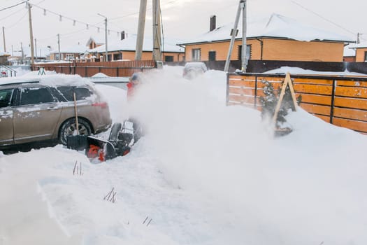 A man clear snow from backyard with snow blower. Winter season and snow blower equipment.