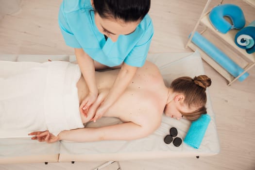 Masseuse doing a therapeutic back massage to a girl in the spa