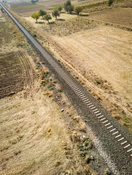 Top view of the train track passing through the arid land, taken with a drone