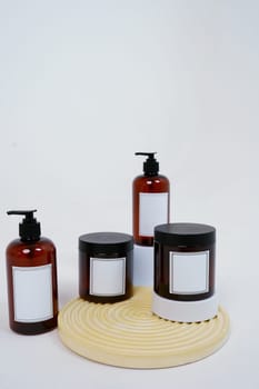 Body care. a set of bottles with dispensers and jars of body cream on a geometric stand and on a light gray background. Advertising concept. High quality photo