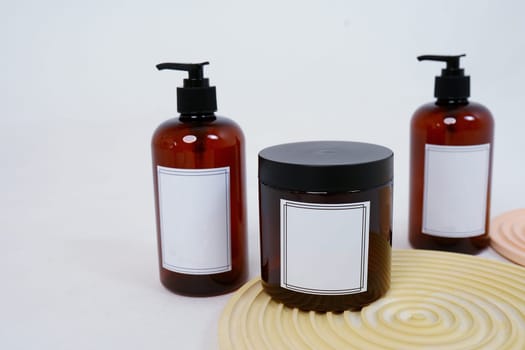 Body care. two bottles with a dispenser and a jar of body cream on a geometric stand on a light gray background. Advertising concept. High quality photo