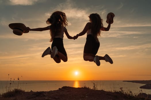 Mom and daughter jumping over the sea beach at sunset, the concept of a long-awaited vacation.