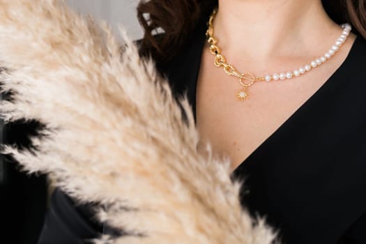 Close-up female in modern gold metal necklace chain with pearl pendant.
