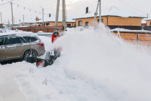 A man clear snow from backyard with snow blower. Winter season and snow blower equipment.